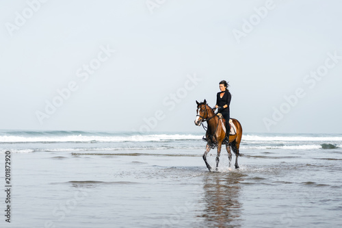 female equestrian riding horse in wavy water