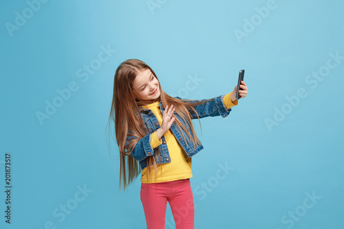 The happy teen girl standing and smiling against blue background. © master1305