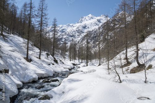 Alpine valley with snow in spring, creek swollen by thaw © Arcansél