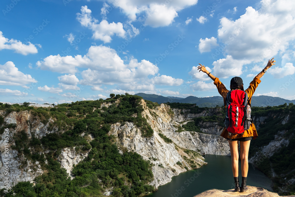 Hiker woman cheering successful woman backpacker open arms on mountain peak