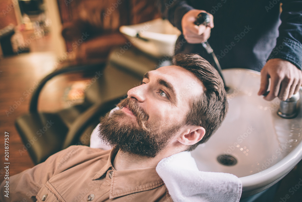 Nice guy is having some care about his hair. The hairdresser is washing his hair. The customer is relaxed and feel happy. Nice guy is having some care about his hair. The hairdresser is washing his hair. The customer is relaxed and feel happy.