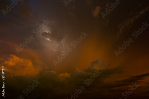 Stroke of lightning with storm clouds and golden sunset light