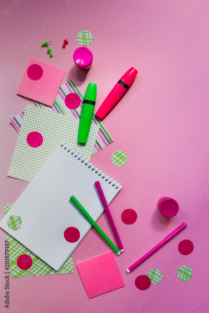 Pink and green markers and notepad for writing on a pink background flat top view with copy space, pattern from stationery accessories for school Pink and green markers and notepad for writing on a pink background flat top view with copy space, pattern from stationery accessories for school