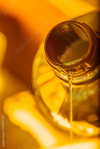 Liquid stream of motorcycle motor oil flows from the neck of the bottle close-up.