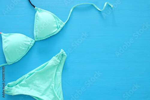 vacation and summer image with sea life style objects and mint bikini over blue wooden background.