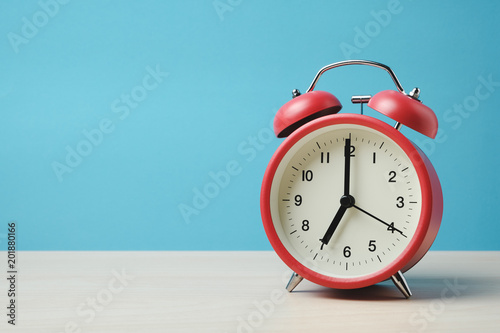 Red vintage alarm clocks on wooden table and light blue background wall