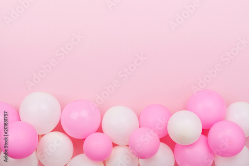 Border from colorful balloons for birthday on pastel pink table top view. Flat lay style.