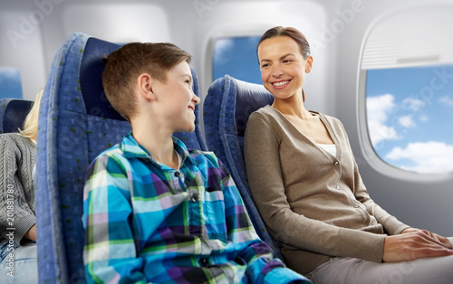 travel, tourism and family concept - happy mother and son sitting in plane and talking over porthole background © Syda Productions
