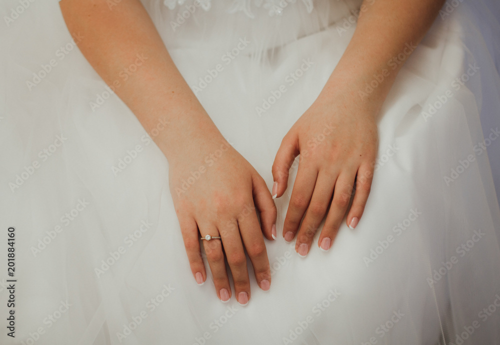 Elegant french manicure for wedding day. Bride is holding her hands with nice nails and engagement ring on white tulle puffy dress. Elegant french manicure for wedding day. Bride is holding her hands with nice nails and engagement ring on white tulle puffy dress.
