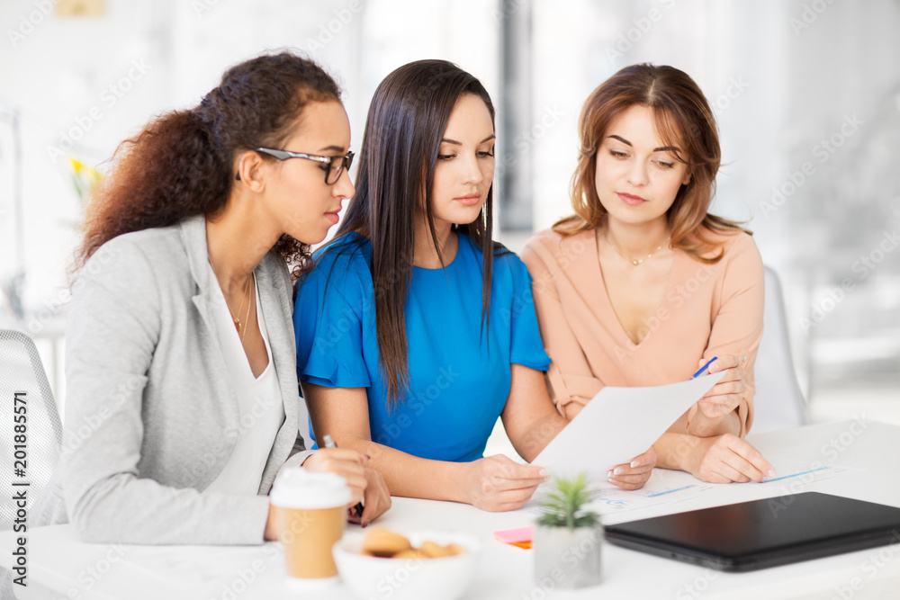 business, teamwork and people concept - female team or businesswomen discussing papers at office business, teamwork and people concept - female team or businesswomen discussing papers at office