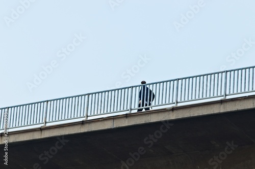 An unidentifiable man walking alone on a bridge in Bangkok, Thailand. 