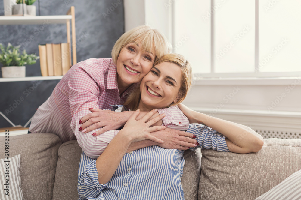 Adult mother and daughter embracing at home