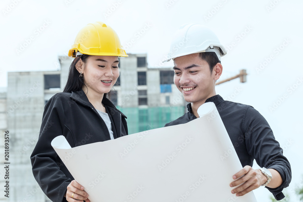 Happy Engineer man and woman looking in blueprint and discuss at construction site Happy Engineer man and woman looking in blueprint and discuss at construction site
