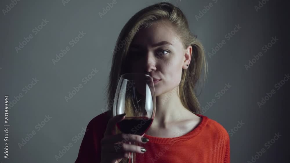 Beautiful girl in a dress drinking red wine in the dark. Close-up. Portrait. 4k Beautiful girl in a dress drinking red wine in the dark. Close-up. Portrait. 4k
