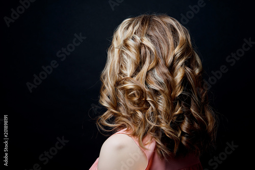 Hairstyle short curls back view of turning the head to the left on a black background. Female professional hairstyle.