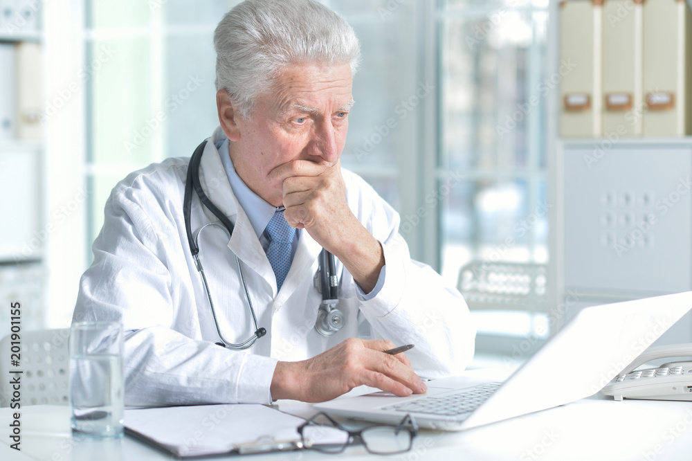 confident senior male doctor with stethoscope working in office confident senior male doctor with stethoscope working in office