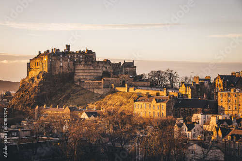 Edinburgh Castle taken at golden hour, a sunburst reflecting from the window and with orange tones photo