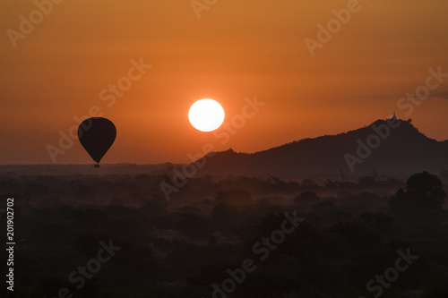 Scenic sunrise with a hot air balloon above Bagan in Myanmar.