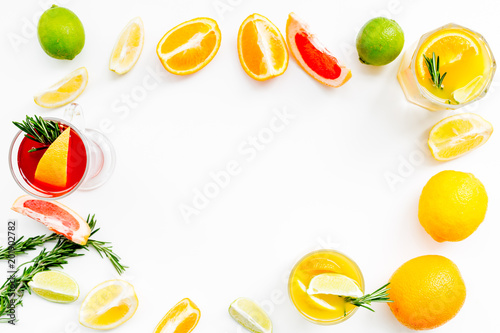 Concept of alcoholic cocktail with fruits. Glass with beverage near oranges  grapefruit  lime and rosemary on white background top view copy space