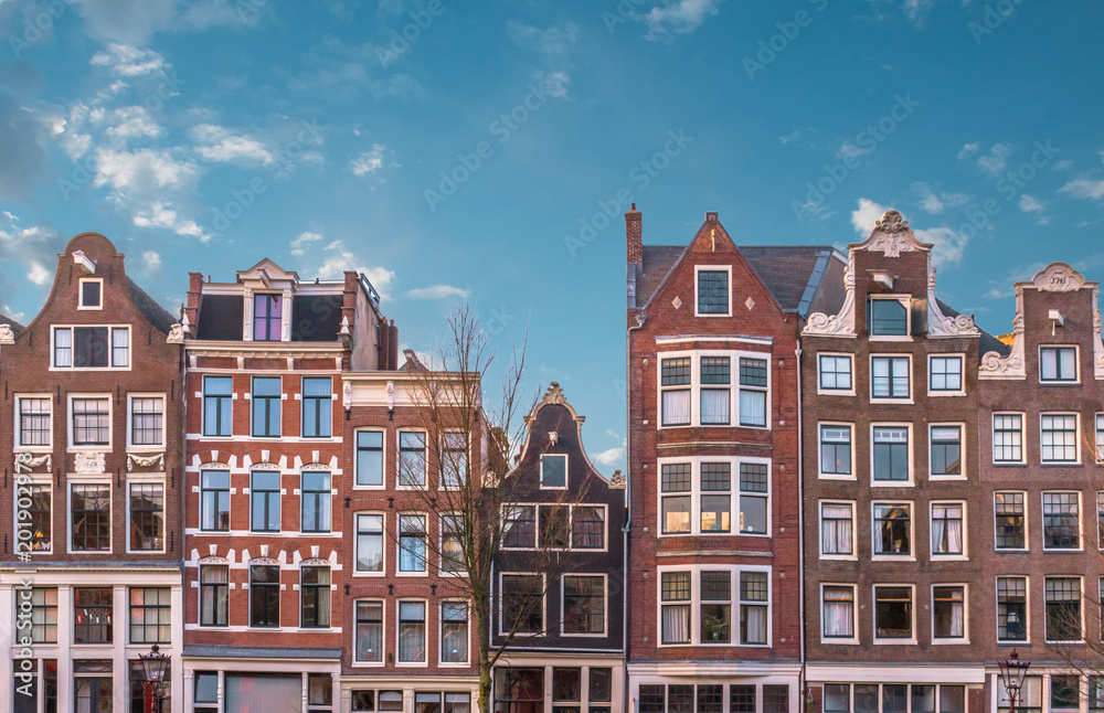 Traditional dutch houses on canal in Amsterdam, Netherlands. Beautiful colorful sky at sunset