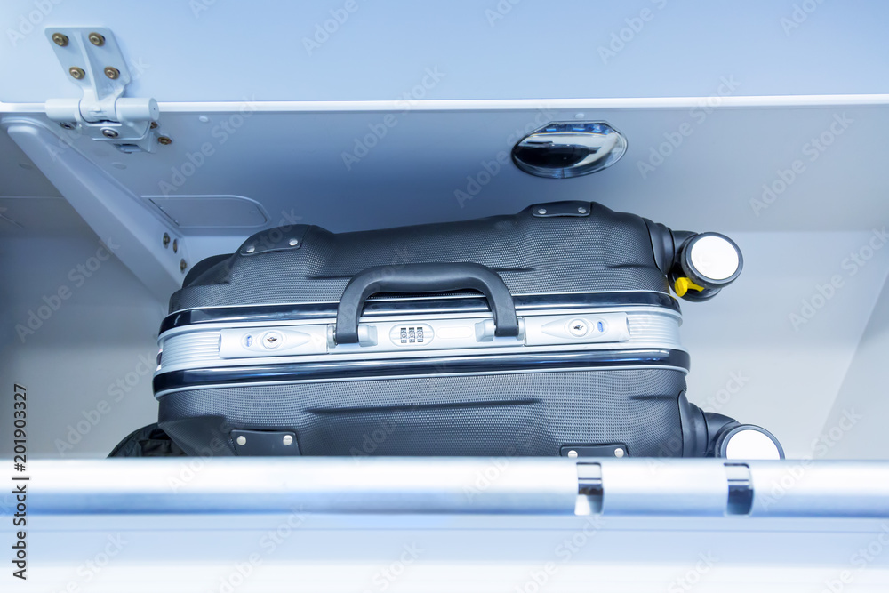 Fototapeta premium Luggage shelf with luggage suitcase in an airplane. Aircraft interior. Travel concept.