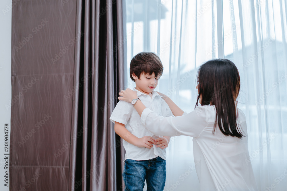 Mother dressing up a son for beginner school lessen and first day at room to going kindergarten education, parent protection boy concept. Mother dressing up a son for beginner school lessen and first day at room to going kindergarten education, parent protection boy concept.