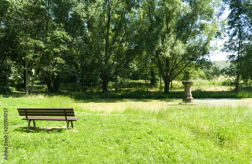 Altenburg / Germany: Idyllic bench at the so called „Fairytale Fountain“, a small pond with the remains of a historic drinking trough for horses on the outskirts of the former residential city photo