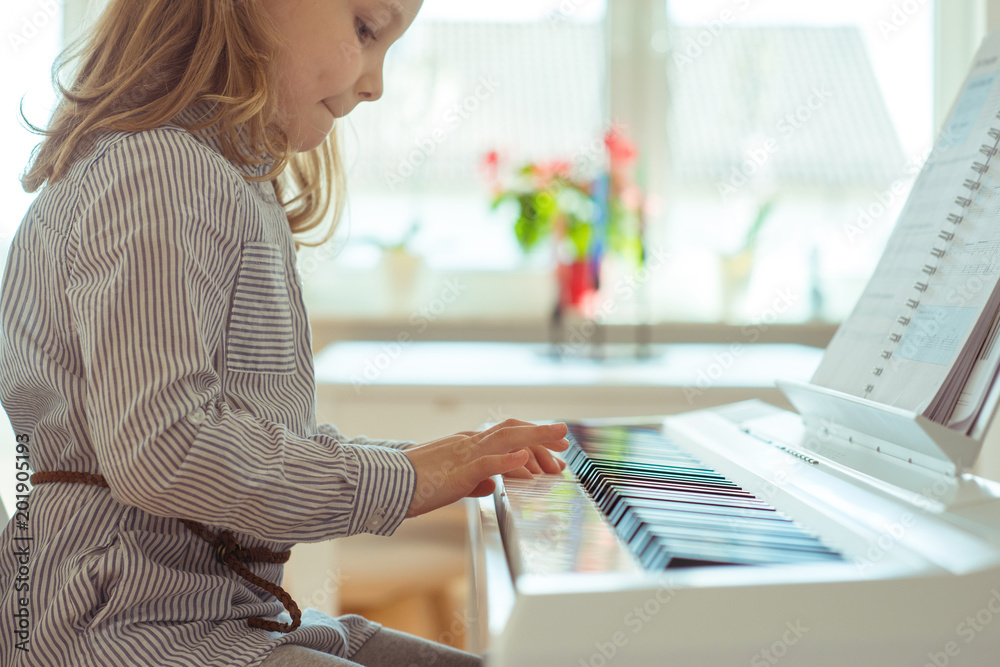 Fototapeta Cute little girl has training with piano