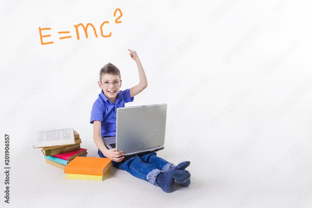 Portrait of cute schoolboy sitting with books and typing on laptop keyboard Portrait of cute schoolboy sitting with books and typing on laptop keyboard