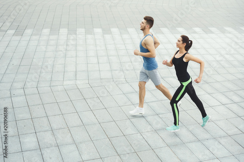 Young woman and man jogging in city copy space
