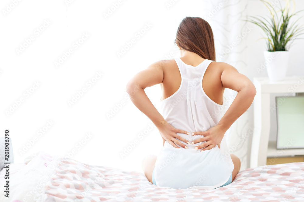 © Kalim - Young woman waking up in bed with backache © Kalim - Young woman waking up in bed with backache