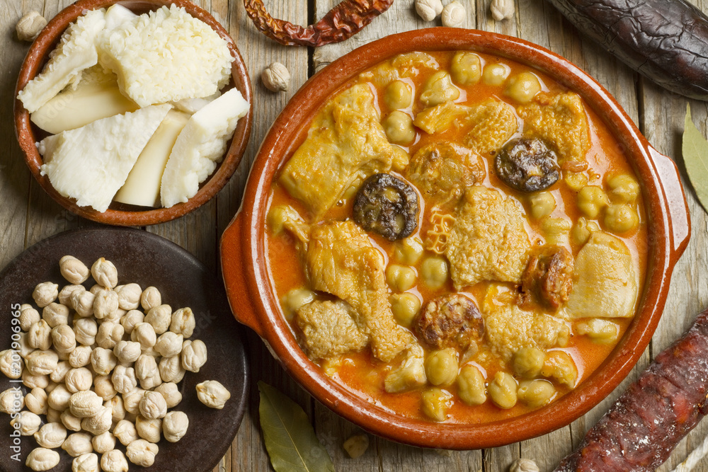 Spanish callos with chickpeas and ingredients on a wooden table Spanish callos with chickpeas and ingredients on a wooden table