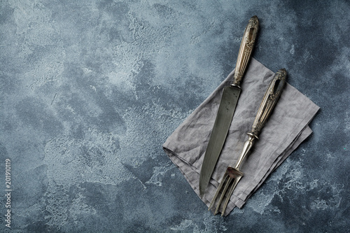 Butcher. Vintage meat knife and fork over a dark gray old stone table. Top view with space for text