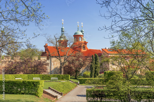 St. Lawrence Church on Petrin hill and surrounding area, the wall, buildngs and beautiful park, garden. Prague, Czech Republic, spring, bright sunny day, shortly after sunrise. photo