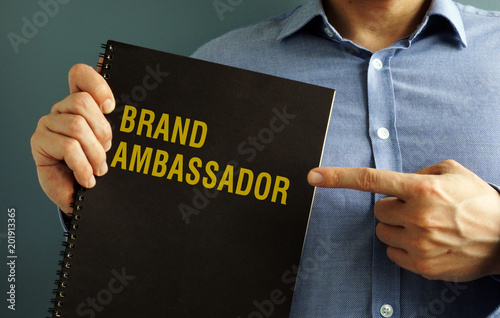 Man is holding book with title Brand Ambassador.