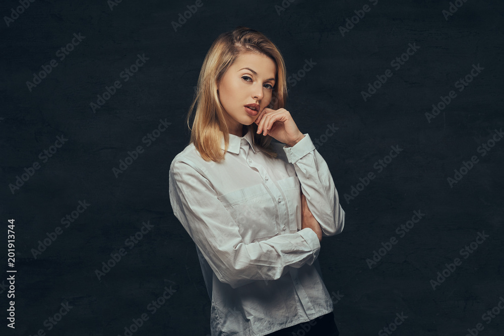 Portrait of a sensual blonde girl dressed in a white shirt, posing in a studio.