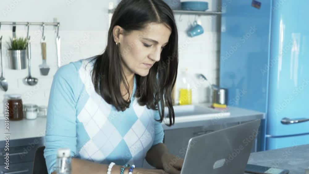 Woman working on laptop by the table at home
Woman working on laptop by the table at home