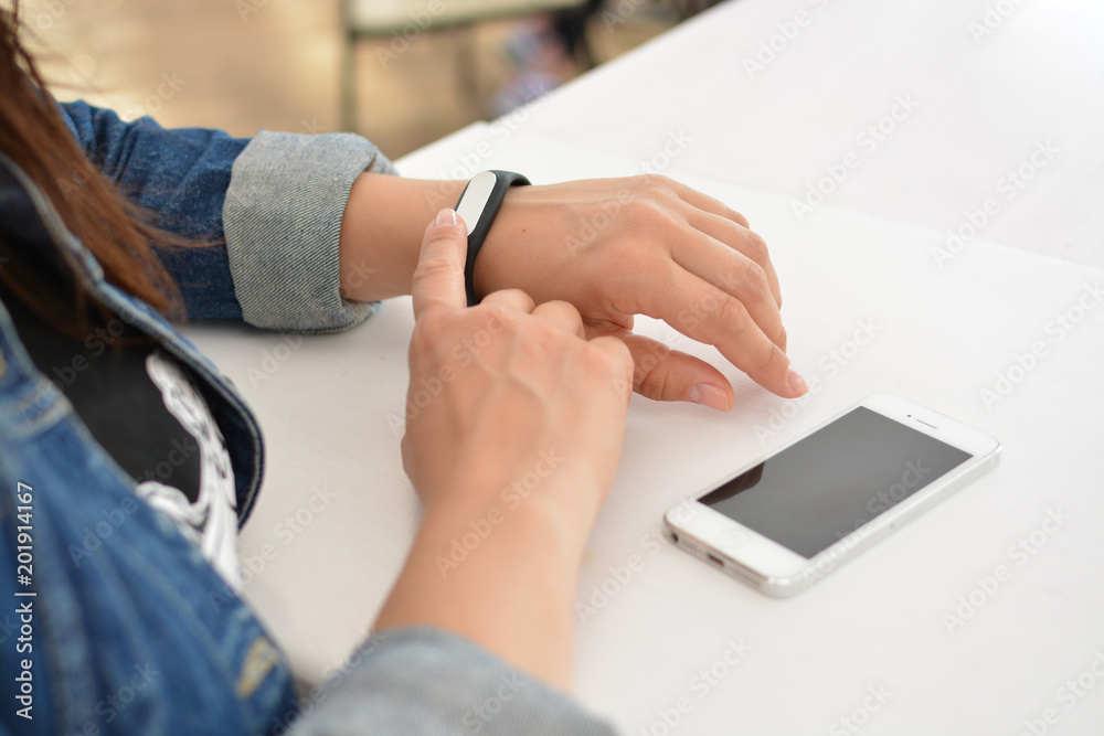 Close-up portrait of a girl using a fitness tracker or heart rate monitor. View the number of steps per day. Fitness concept. A woman looks at the results of training on a fitness bracelet. Close-up portrait of a girl using a fitness tracker or heart rate monitor. View the number of steps per day. Fitness concept. A woman looks at the results of training on a fitness bracelet.