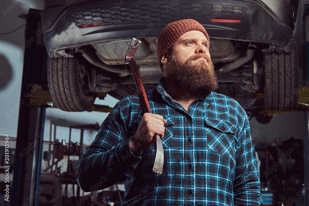 Two bearded brutal mechanics repair a car on a lift in the garage. Two bearded brutal mechanics repair a car on a lift in the garage.