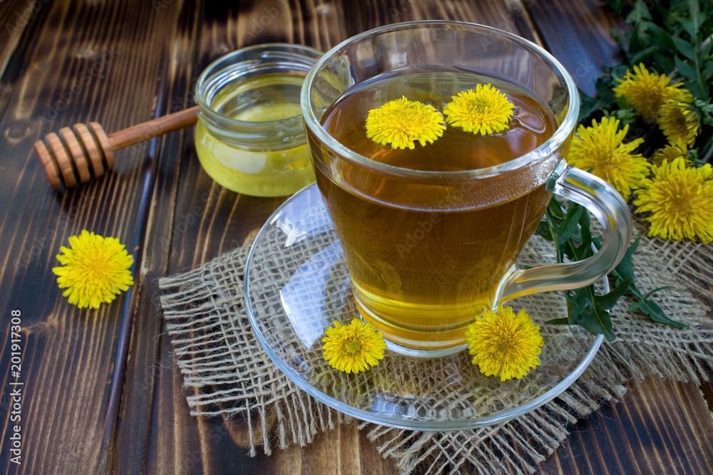 Tea with dandelions in the glass cup on the rustic wooden background Tea with dandelions in the glass cup on the rustic wooden background