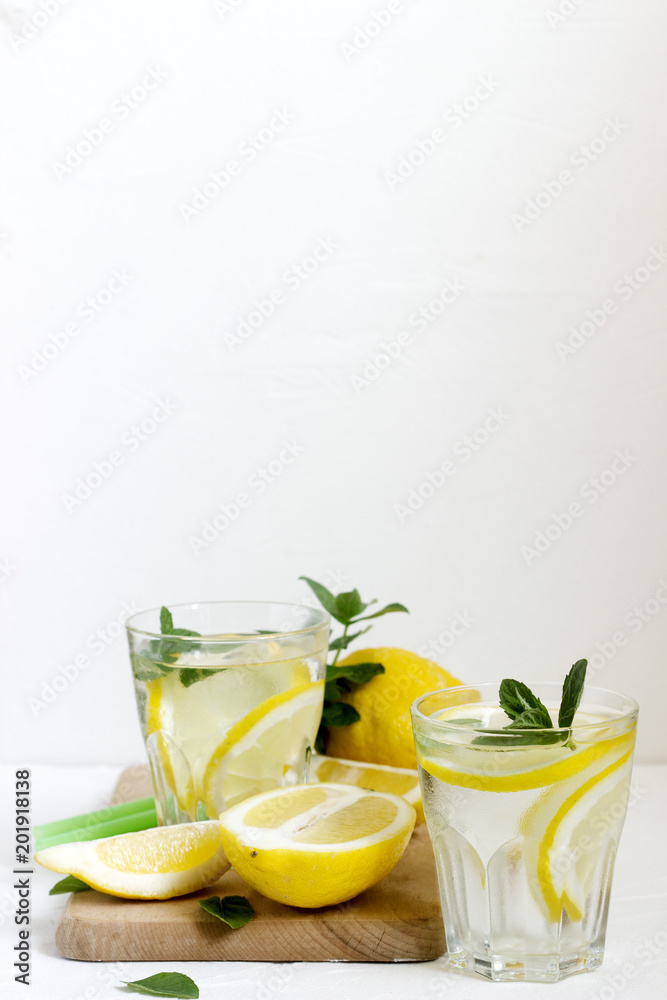Lemonade with lemon slices, mint and ice and lemons on a light concrete background. Rustic style. Lemonade with lemon slices, mint and ice and lemons on a light concrete background. Rustic style.