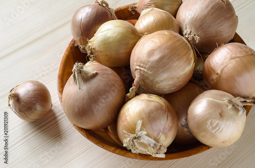 Bulbs in a bowl and one onion on a wooden table