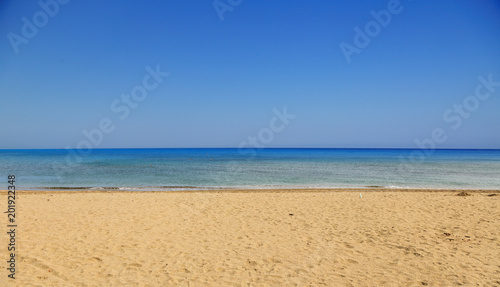 Sandy beach, calm sea, clear blue sky background. Summer destination.