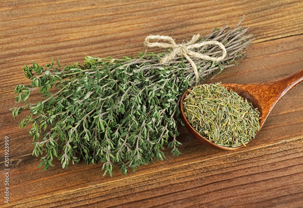 Dried thyme and bundle of thyme sprigs on wooden background Dried thyme and bundle of thyme sprigs on wooden background