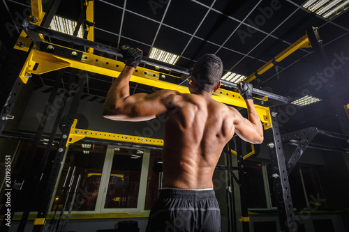 athletic african american man does pull-ups in gym on beam. power pull Up workout. how looks muscles during pulling photo