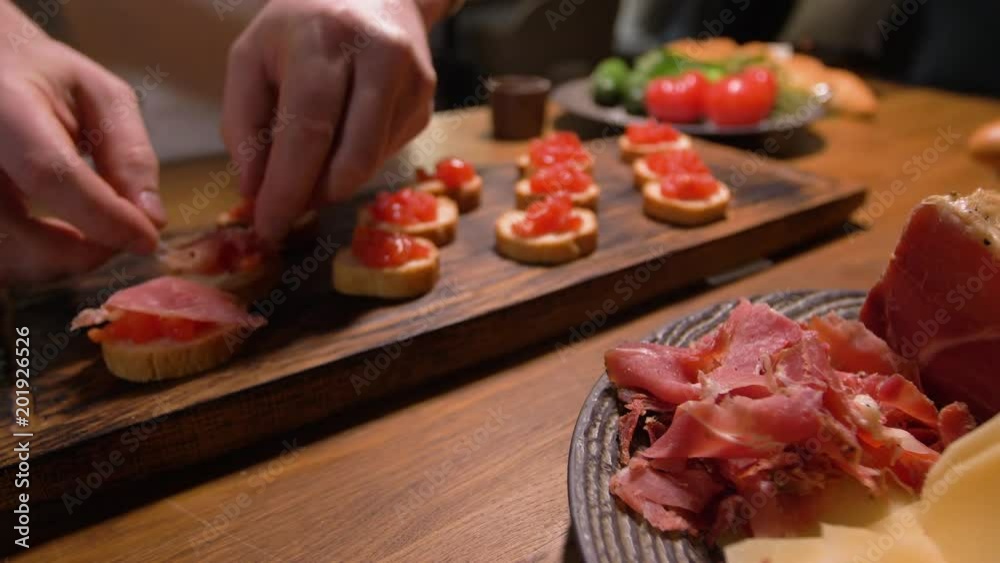 Preparation of Spanish tapas. Unfolding pieces of bacon on a layer of crushed tomatoes.