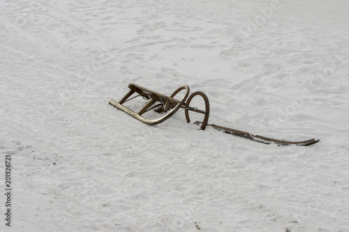 Broken snow sledge. Already useless sled standing alone in the snow.
