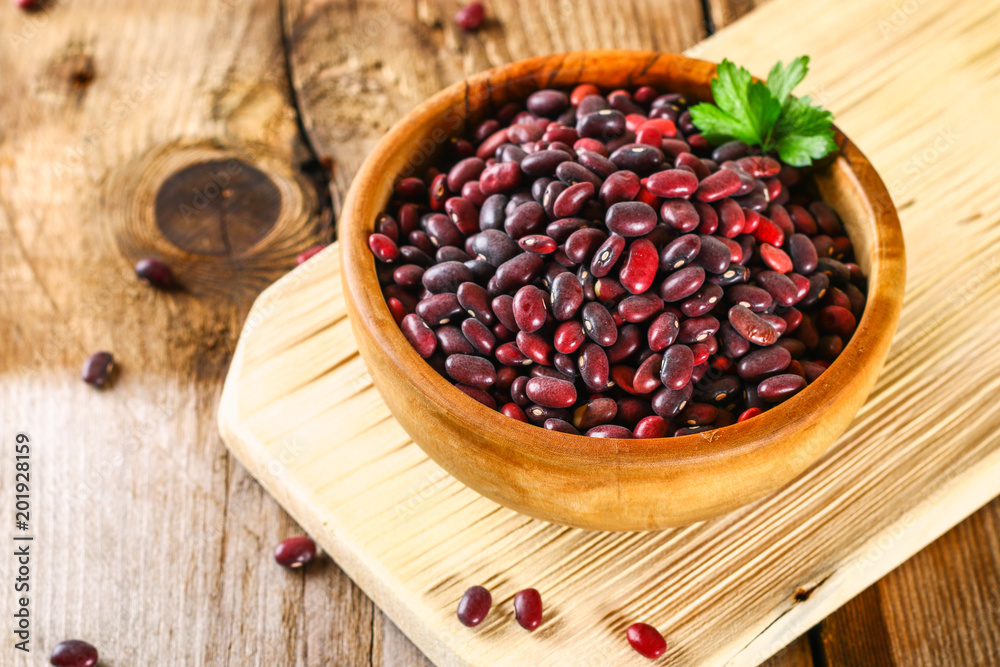 Red raw beans with greens on a wooden table. Red raw beans with greens on a wooden table.
