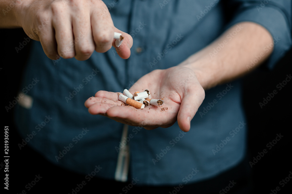 man breaks a cigarette. on black background