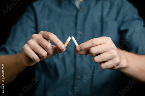man breaks a cigarette. on black background